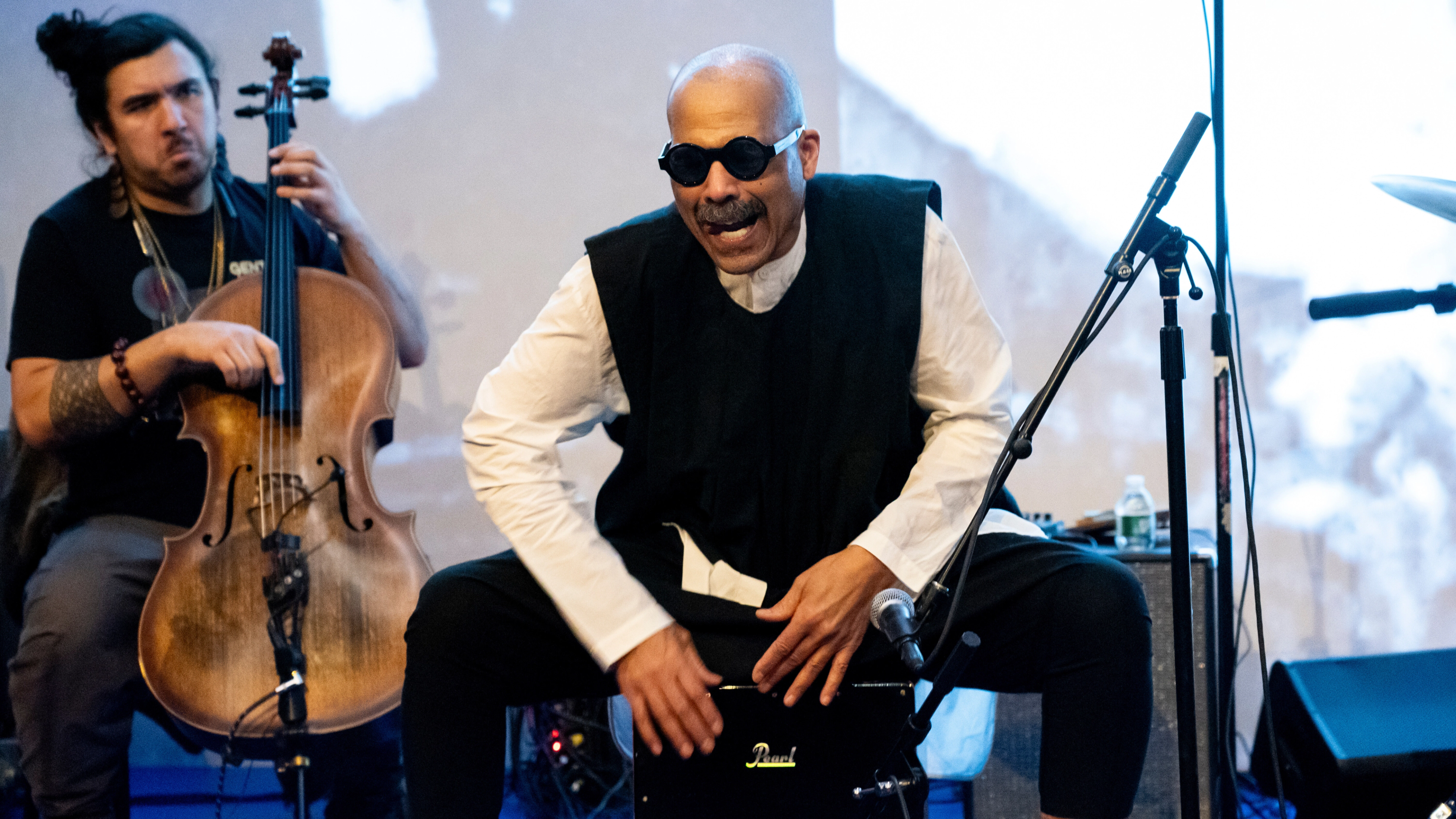 A man sitting on top of a cajon appears to sing.
